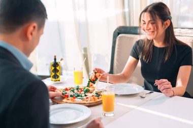 Bir çift bir restoranda pizza yiyor.