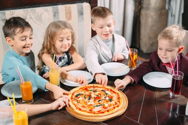 Companhia de crianças comer pizza no restaurante — Fotografia de Stock