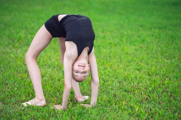 Hermosa niña haciendo gimnasia en la hierba en un día soleado —  Fotos de Stock