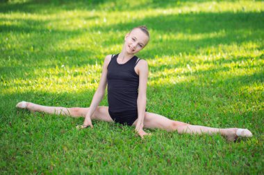 güzel küçük bir kız güneşli bir günde çim jimnastik yapıyor