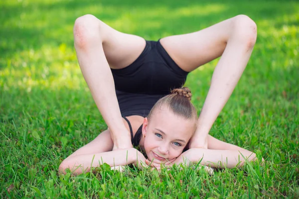 漂亮的小女孩，在一个晴朗的日子做体操在草地上 — 图库照片