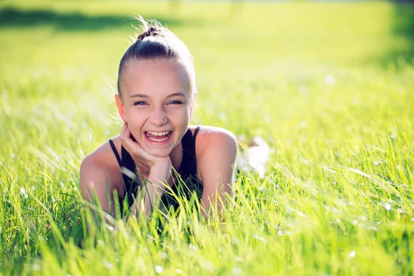 Schattig gelukkig klein meisje liggend op het gras. — Stockfoto