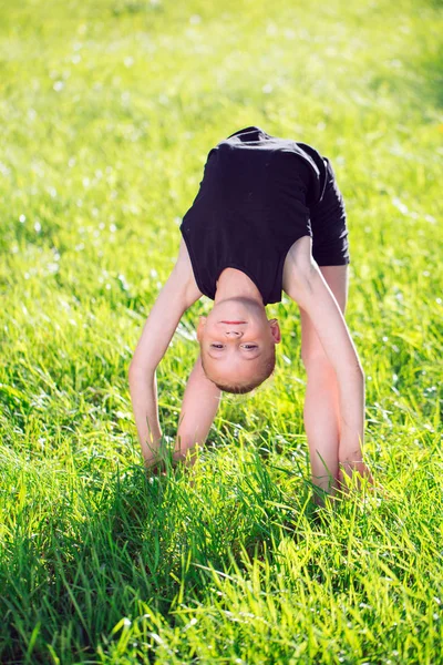Belle petite fille faisant de la gymnastique sur l'herbe par une journée ensoleillée . — Photo