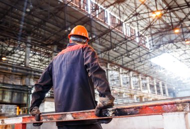 Metalürji tesisinin arka planında çalışan bir adam. işçi yorgun