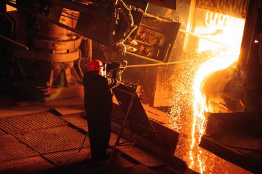 Çelik üretimi için bitki. Elektrikli bir eritme fırını. Fabrika işçisi metal için örnek alıyor..