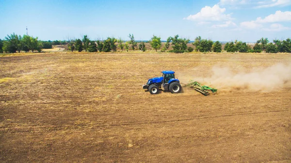 Un tracteur labourant et semant dans le champ . — Photo