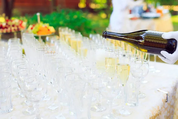 Bartender i vita handskar som häller champagne i glas. — Stockfoto