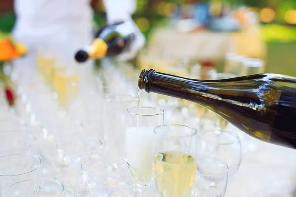 Bartender i vita handskar som häller champagne i glas. — Stockfoto