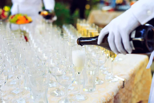 Barmana v bílých rukavicích nalévat šampaňské na brýle. — Stock fotografie