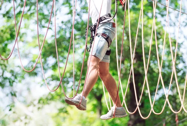 Man spend their leisure time in a ropes course. Man engaged in rope park
