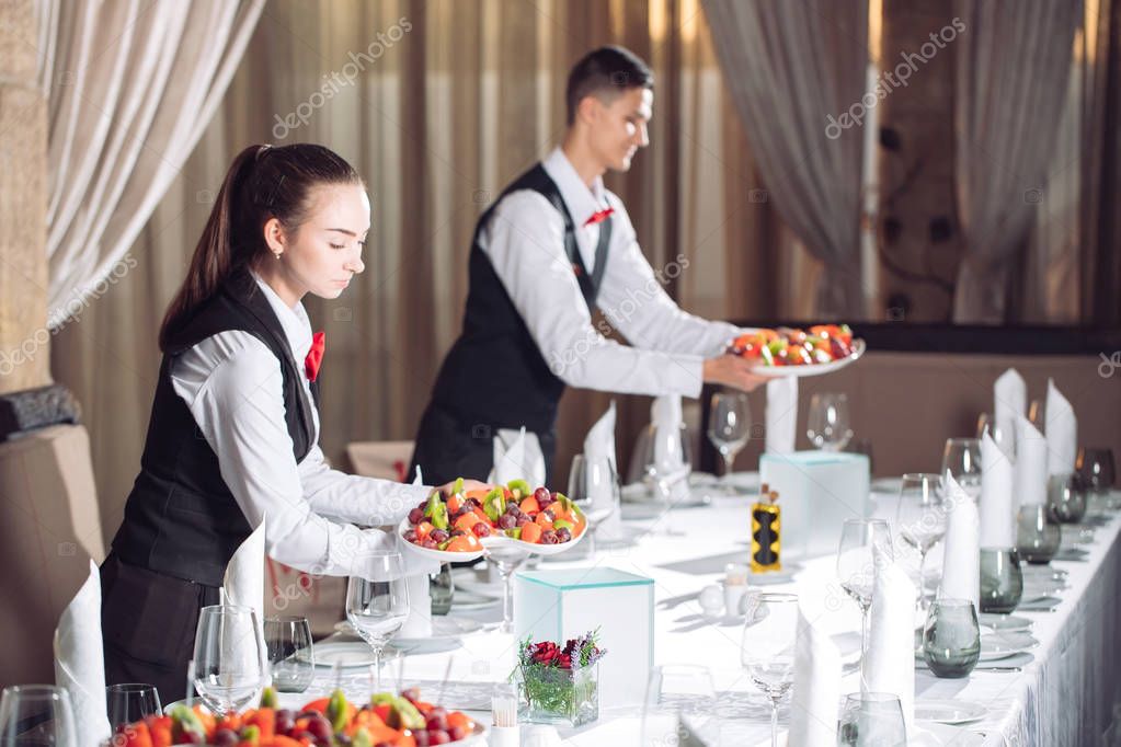 Waiters serving table in the restaurant preparing to receive guests