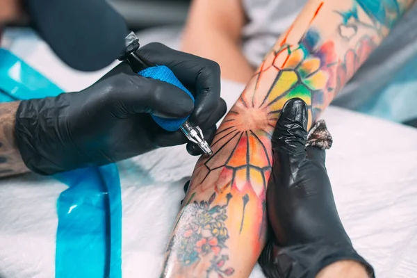 Artista profesional del tatuaje hace un tatuaje en una mano de chicas jóvenes. — Foto de Stock