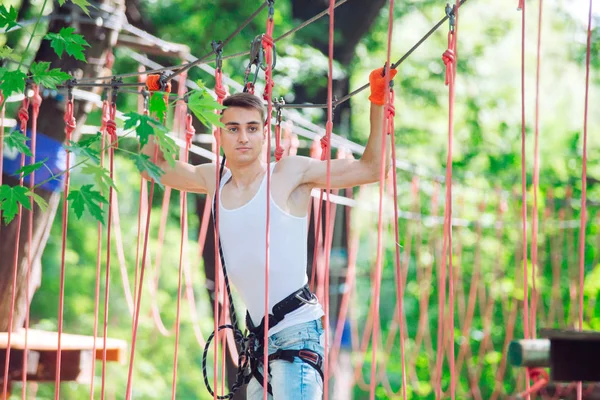 Man spend their leisure time in a ropes course. Man engaged in rope park
