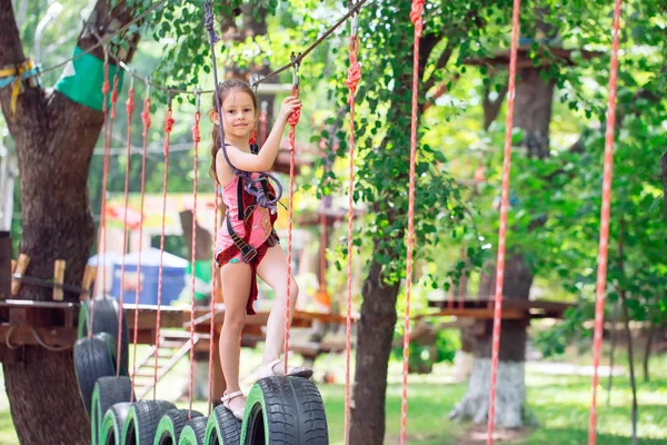 Menina da escola feliz desfrutando de atividade em um parque de aventura de escalada em um dia de verão, — Fotografia de Stock