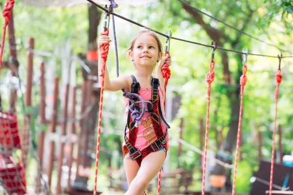 Menina da escola feliz desfrutando de atividade em um parque de aventura de escalada em um dia de verão, — Fotografia de Stock