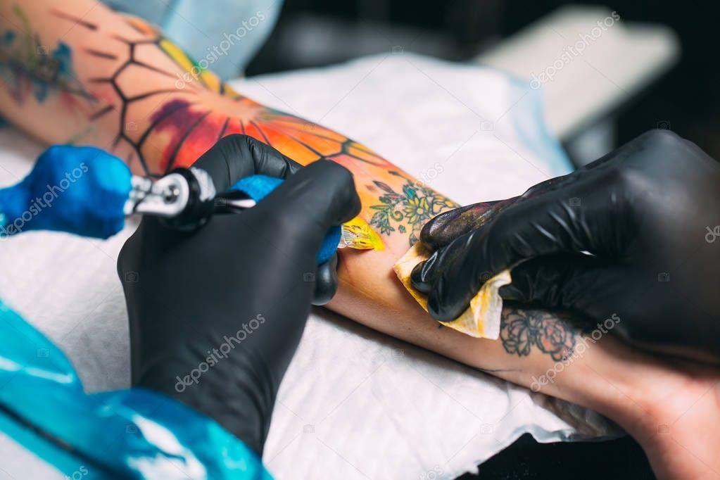 Professional tattoo artist makes a tattoo on a young girls hand.