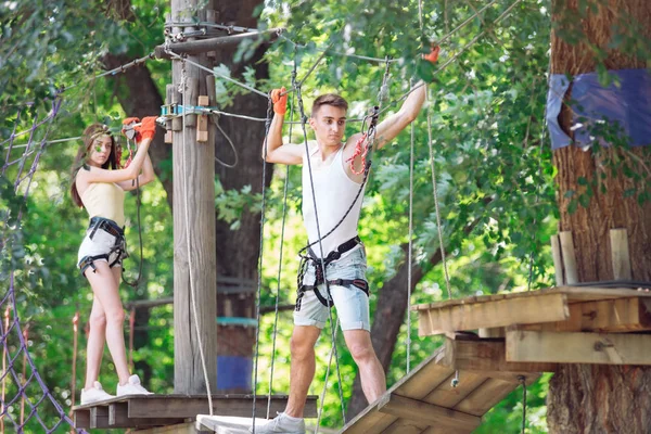 Pareja pasar su tiempo libre en un curso de cuerdas. hombre y mujer dedicados a la escalada en roca, — Foto de Stock