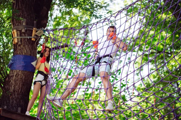 Pareja pasar su tiempo libre en un curso de cuerdas. hombre y mujer dedicados a la escalada en roca, — Foto de Stock