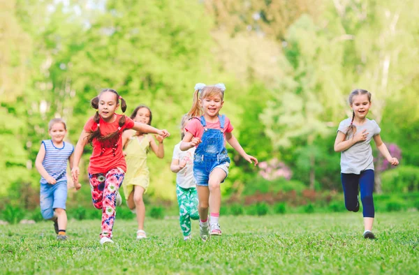 Багато різних дітей, хлопчиків і дівчаток біжать в парку в сонячний літній день в повсякденному одязі — стокове фото