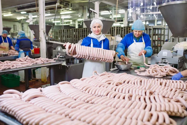 Macellai che lavorano salsicce nella fabbrica di carne . — Foto Stock