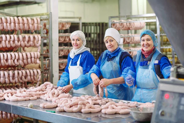 Macellai che lavorano salsicce nella fabbrica di carne . — Foto Stock