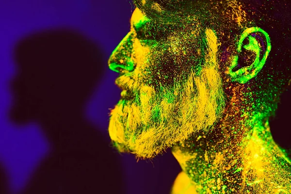 Концепция. Портрет бородатого человека. Человек окрашен в ультрафиолетовый порошок — стоковое фото