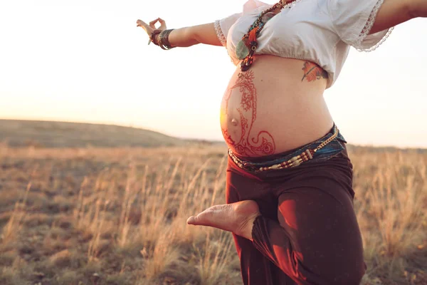 Mulher grávida fazendo ioga no campo ao pôr do sol — Fotografia de Stock