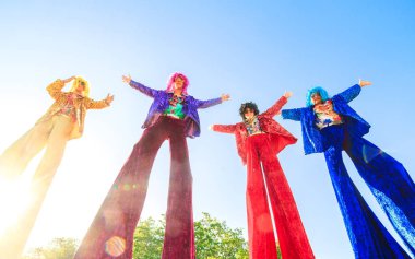 Mavi gökyüzüne karşı poz veren ayaklıklar üzerinde gençler.