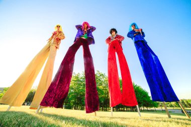 Young people on stilts posing against the blue sky. clipart