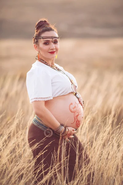 Schwangere Frau entspannt sich in der Natur an einem schönen sonnigen Tag. Schwangerer Bauch mit Feld im Hintergrund — Stockfoto