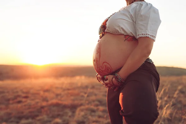 Беременная женщина занимается йогой в поле на закате — стоковое фото