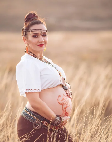 Έγκυος γυναίκα που χαλαρώνει στη φύση σε μια όμορφη ηλιόλουστη μέρα. έγκυες γυναίκες στομάχι με χωράφι στο παρασκήνιο — Φωτογραφία Αρχείου
