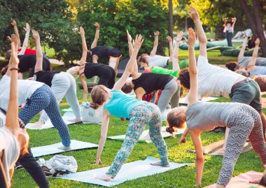 Bir grup genç gün batımında Park'ta yoga yapıyor..
