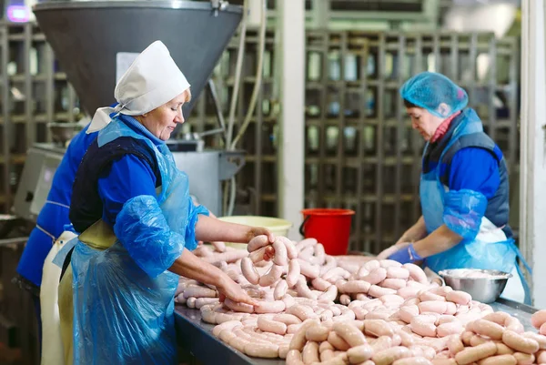 Macellai che lavorano salsicce nella fabbrica di carne . — Foto Stock