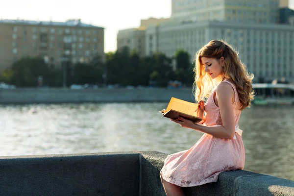 Mladá dívka, která čte knihu o řece bank — Stock fotografie