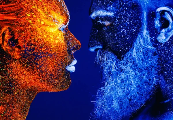 Conceito. Retrato de um homem e uma mulher barbudos pintados em pó ultravioleta — Fotografia de Stock