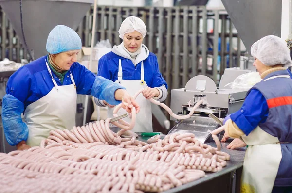 Macellai che lavorano salsicce nella fabbrica di carne . — Foto Stock