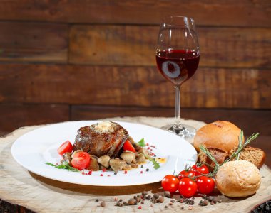 Ahşap bir masanın arka planında beyaz bir tabak üzerinde mantar ile et yemeği.