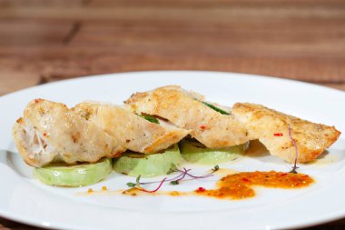 Ahşap bir masanın arka planında beyaz bir tabak üzerinde brokoli püresi ile domuz bonfile.