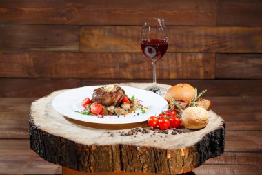 Ahşap bir masanın arka planında beyaz bir tabak üzerinde mantar ile et yemeği.