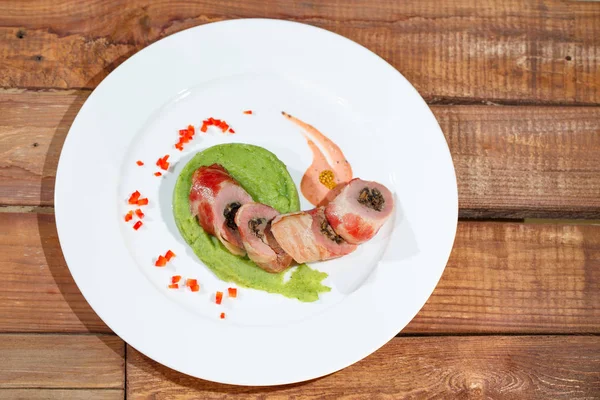 Pork tenderloin with broccoli puree on a white plate on the background of a wooden table. — Stock Photo, Image