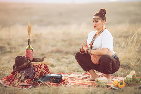 Gravid kvinna som gör yoga på fältet vid solnedgången — Stockfoto