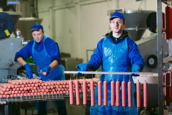 Retrato de açougueiros processando salsichas na fábrica de carne . — Fotografia de Stock