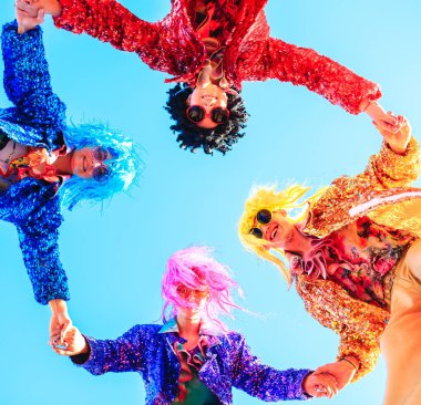 Mavi gökyüzüne karşı poz veren ayaklıklar üzerinde gençler.