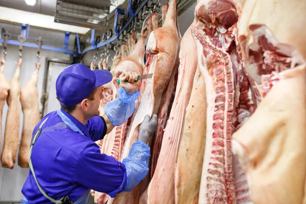 Carnicero cortando carne de cerdo en la fabricación de carne — Foto de Stock