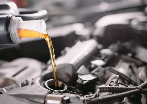 Aceite de motor que vierte al motor del coche. Una estación de servicio . —  Fotos de Stock