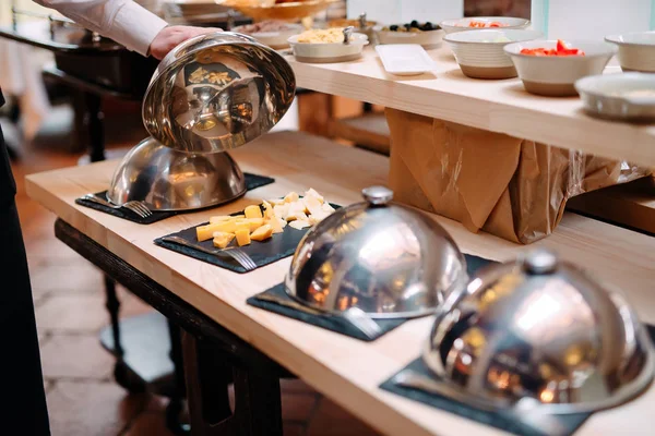 Kaas snijden op een metalen kom met een dop. Ontbijt in het hotel of restaurant. — Stockfoto