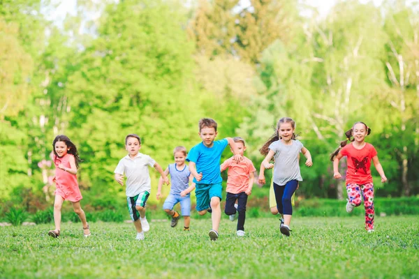 Many different kids, boys and girls running in the park on sunny summer day in casual clothes Stock Picture