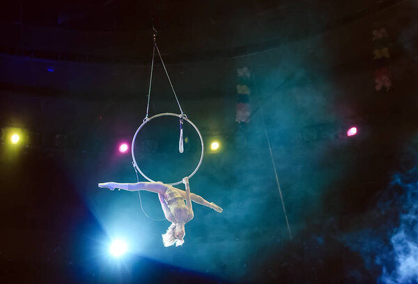 Aerial acrobat in the ring. A young girl performs the acrobatic elements in the air ring.