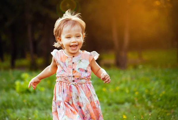 Feliz niña linda corriendo sobre el césped en el parque. Felicidad . —  Fotos de Stock